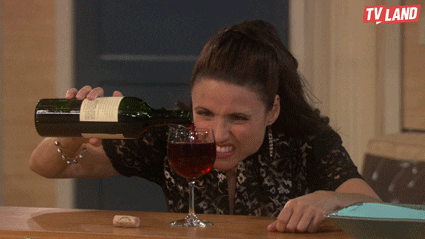 GIF of a woman pouring red wine with a frustrated expression at a table.