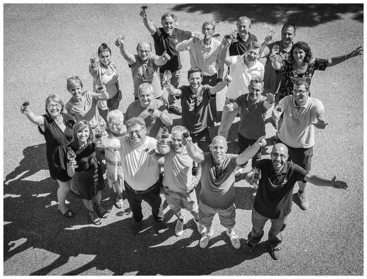 Cave de Cairanne team with arms raised, on a paved area.