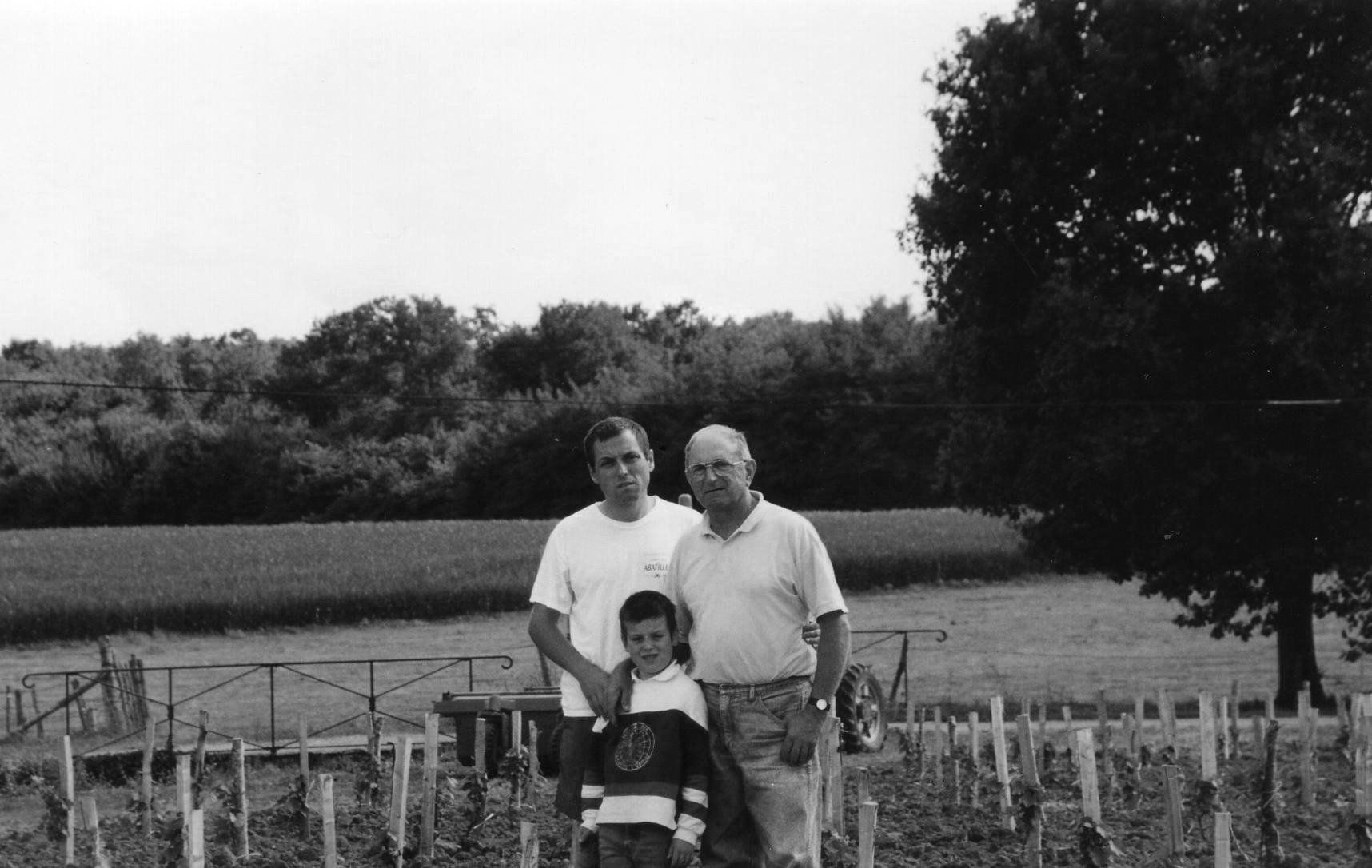 Champ des Treilles family posing for photo in field. A field and trees in the background.