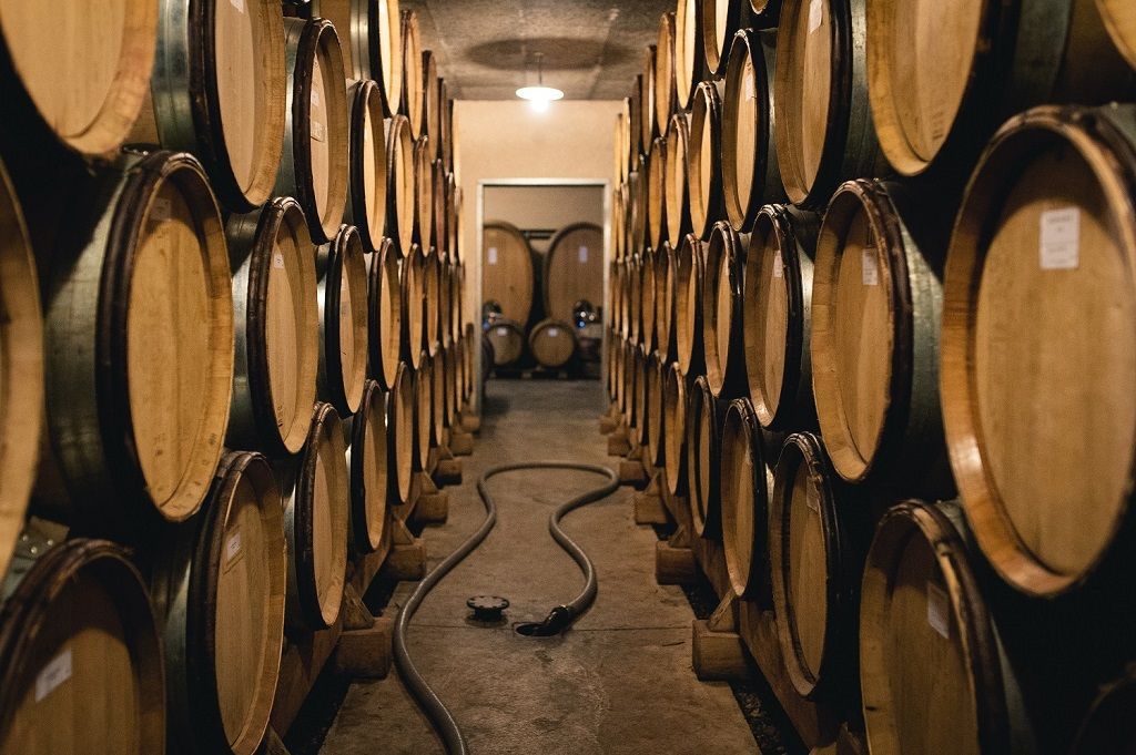 Wine barrels stacked in Francois Villard cellar, forming a long, central pathway.