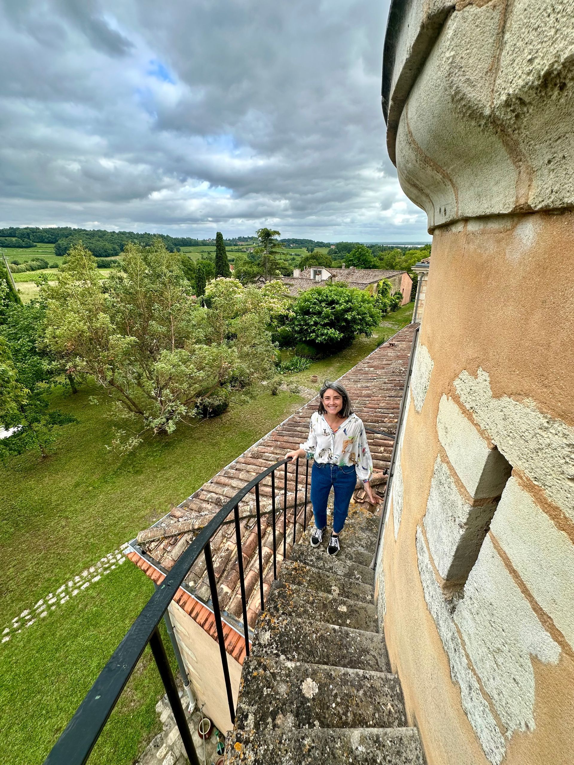Woman on stone steps at Peybonhomme-les-Tours, overlooking a green landscape.