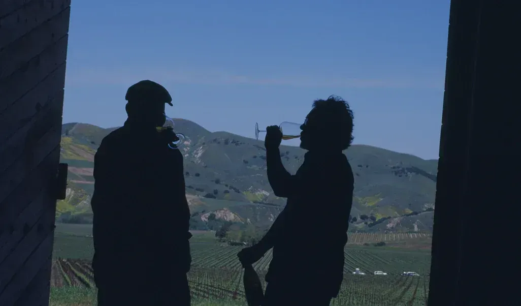 Silhouetted figures drinking wine in a doorway overlooking Sandhi vineyard