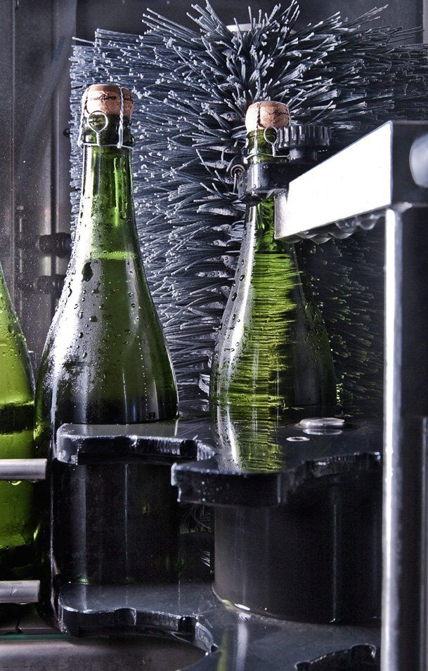 Suriol - Cava bottles in an automated washing machine, getting cleaned by rotating brushes.